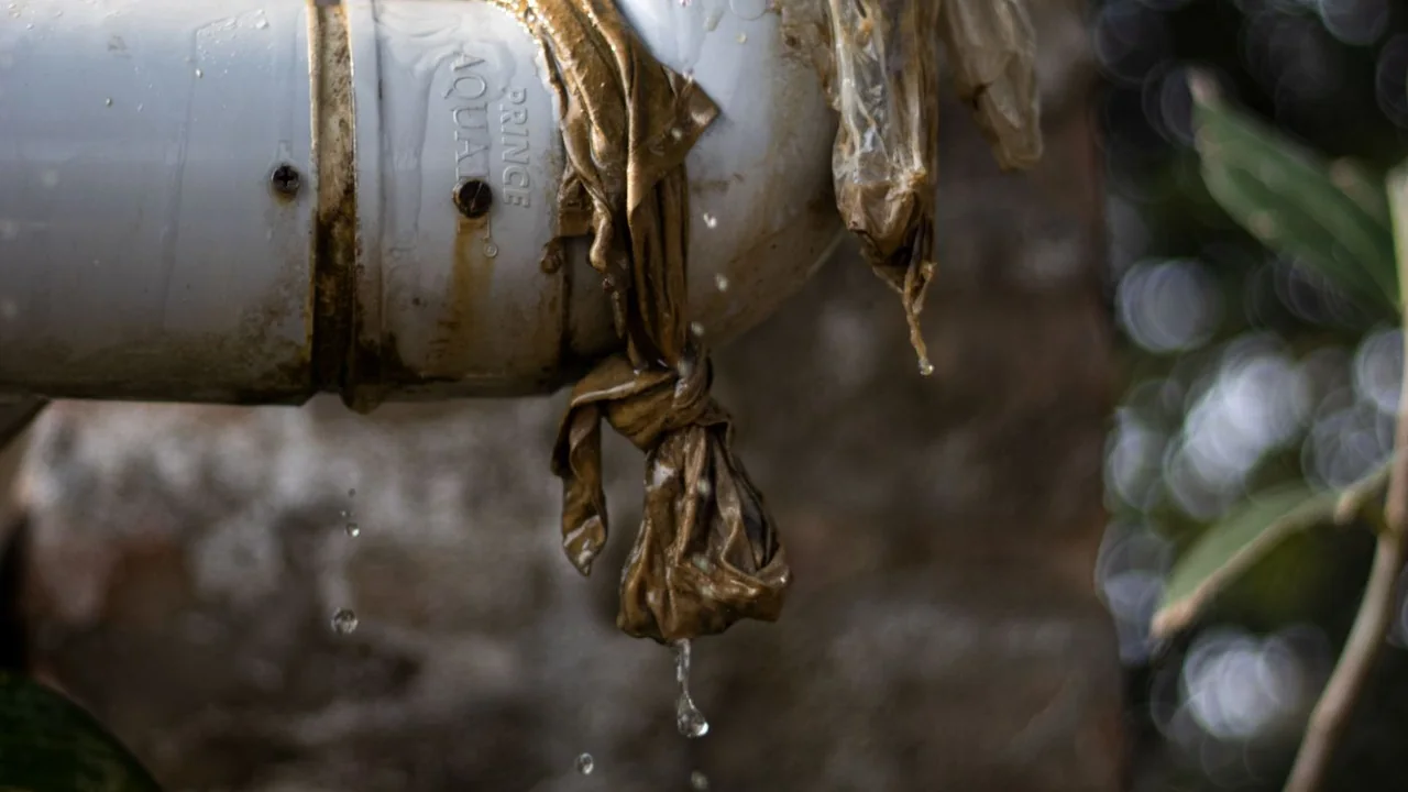 Water dripping from a failed joint on an exterior white pipe