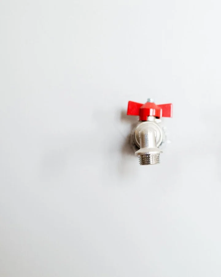 Red-handled isolation valve fitted to a white wall