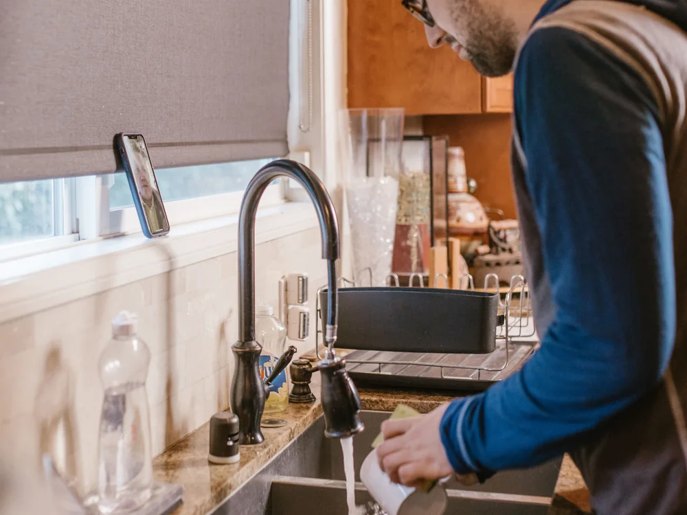 Homeowner running water at a kitchen sink with a black mixer tap