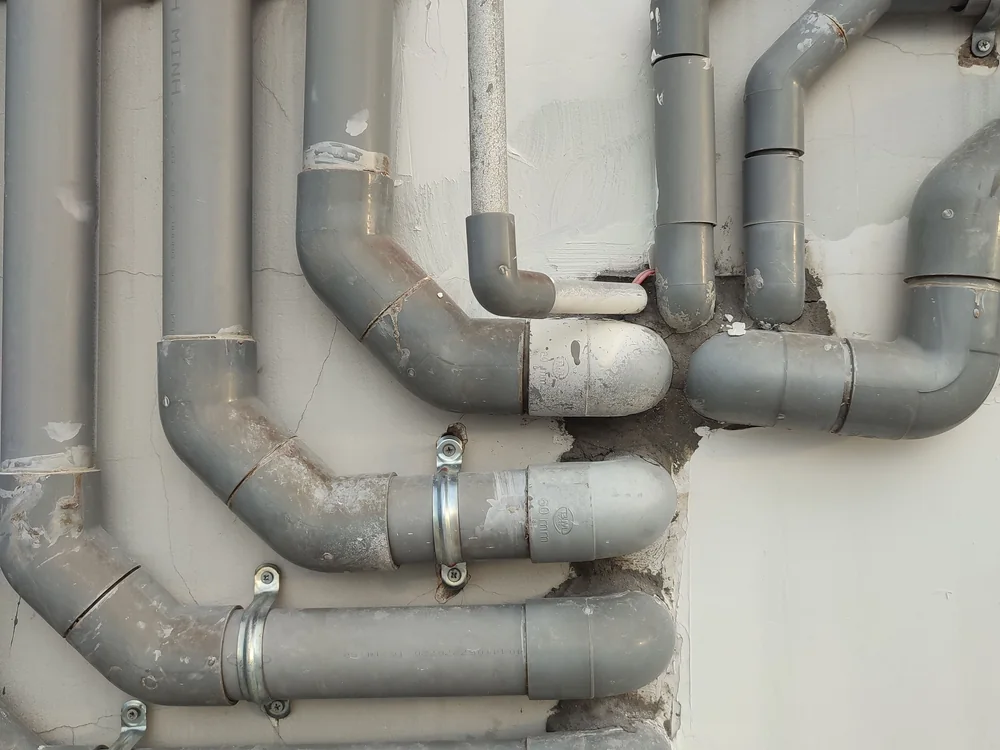 Grey PVC waste pipework running across a basement wall