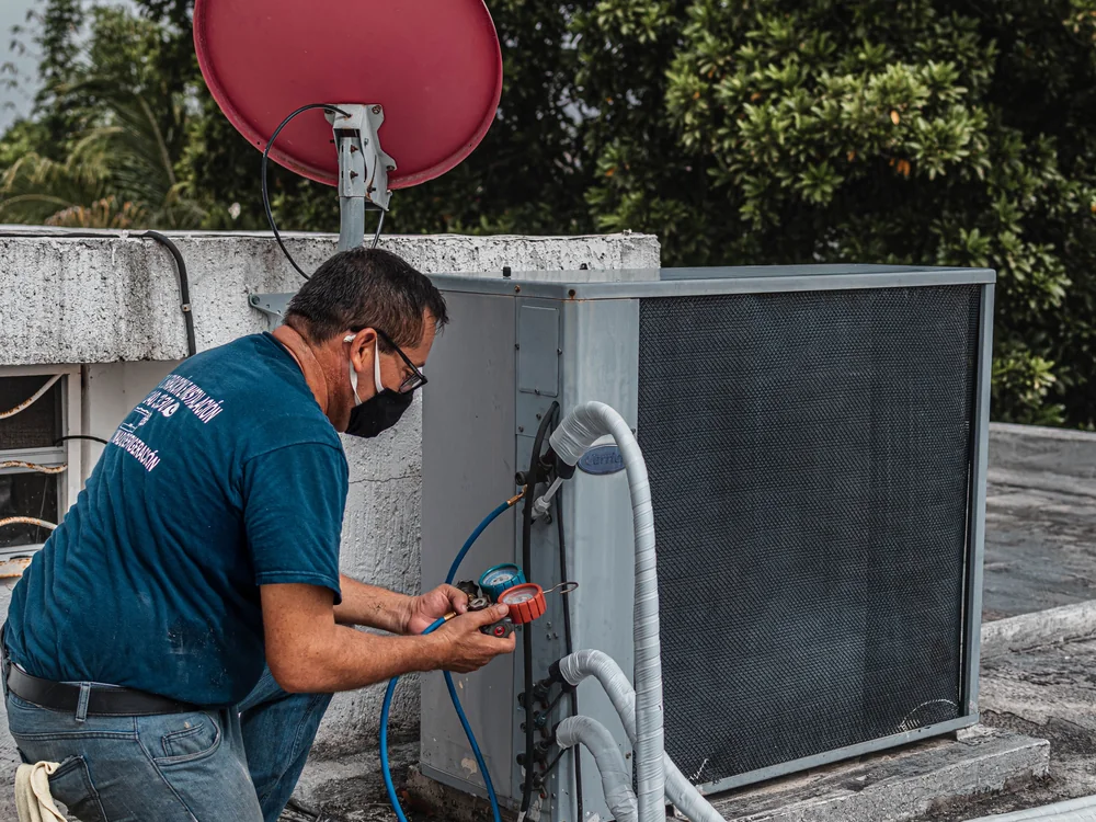 Technician testing the controls on an outdoor heat pump unit